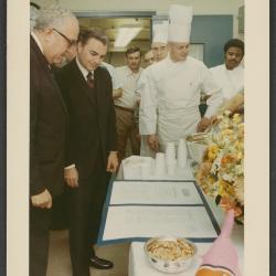 In this photograph, taken February 24, 1971, White House Chief Usher Rex Scouten presents Maitre d'hotel John W. Ficklin with an award certificate during a staff event honoring Ficklin's service. The event possibly was held to commemorate Ficklin's 30th anniversary as a member of the White House staff. Ficklin served as a member of the White House domestic staff for 43 years prior to his retirement in 1983.

This photograph is part of a collection belonging to former White House Executive Chef Henry Haller.  Haller served as executive chef of the White House from 1966-1987. Haller can be seen standing behind the table in the center of this photograph.